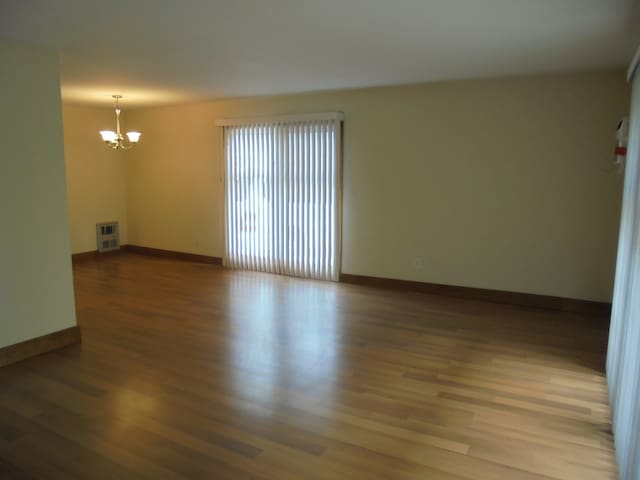 spare room featuring a chandelier and wood-type flooring