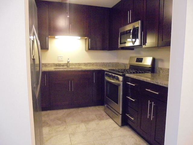 kitchen featuring light tile patterned flooring, light stone countertops, stainless steel appliances, and sink