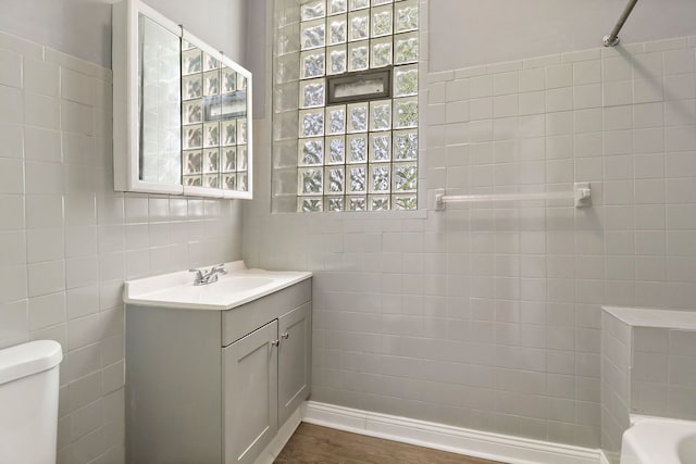 full bathroom with tile walls, vanity, tiled shower / bath combo, hardwood / wood-style floors, and toilet