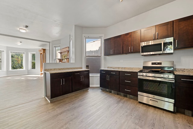 kitchen featuring dark brown cabinets, stainless steel appliances, light hardwood / wood-style floors, and light stone countertops