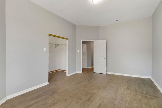 unfurnished bedroom with hardwood / wood-style floors, a closet, and a walk in closet