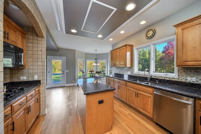 kitchen with a wealth of natural light, black appliances, tasteful backsplash, and a kitchen island