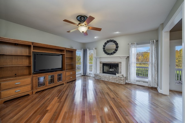 unfurnished living room featuring ceiling fan, wood-type flooring, a healthy amount of sunlight, and a fireplace