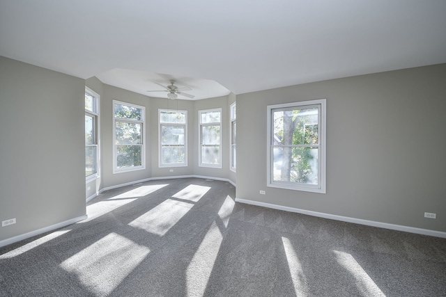 unfurnished room with dark colored carpet, ceiling fan, and plenty of natural light