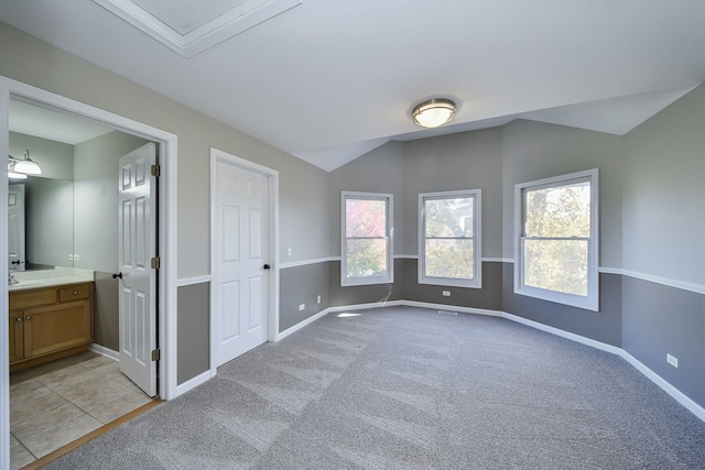 unfurnished bedroom with light carpet, sink, vaulted ceiling, and connected bathroom