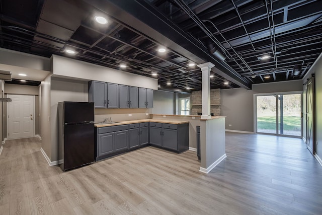 kitchen featuring ornate columns, light wood-type flooring, black fridge, and gray cabinets