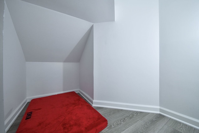 additional living space with vaulted ceiling and dark colored carpet