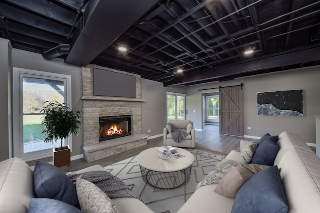 living room featuring a barn door, wood-type flooring, and a fireplace