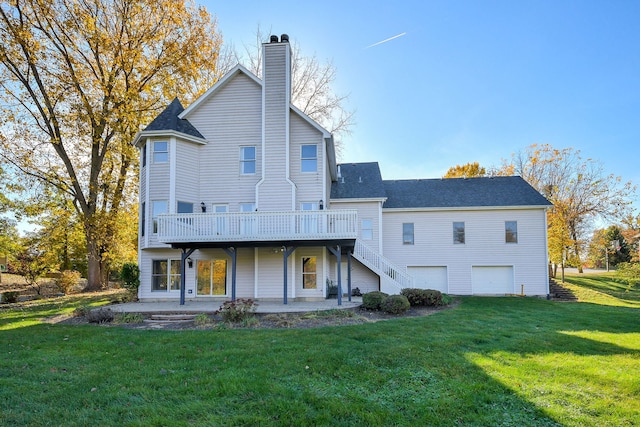 rear view of house featuring a garage, a lawn, and a deck