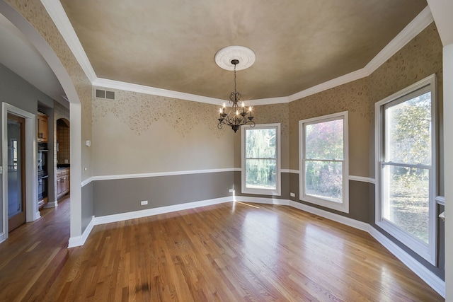 empty room with hardwood / wood-style flooring, ornamental molding, and plenty of natural light