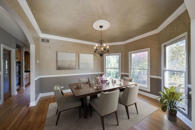 dining area featuring wood-type flooring, plenty of natural light, and ornamental molding