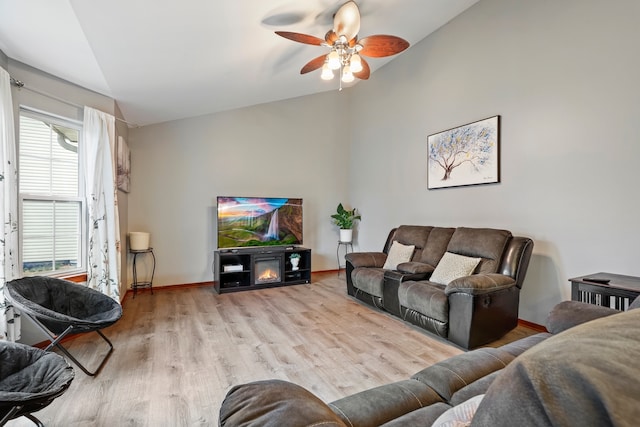 living room with light hardwood / wood-style floors, vaulted ceiling, and ceiling fan