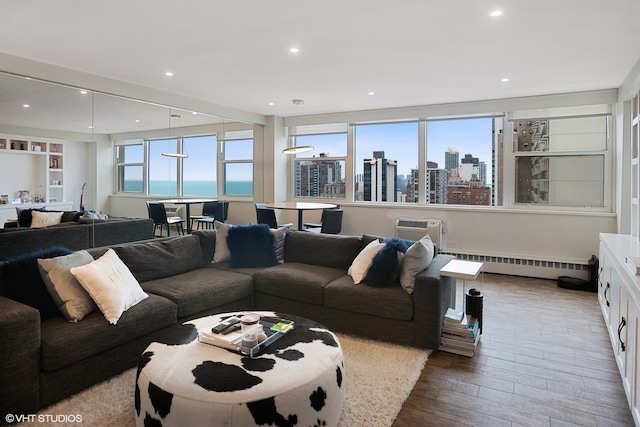 living room featuring a water view, a wall unit AC, hardwood / wood-style flooring, and a baseboard heating unit