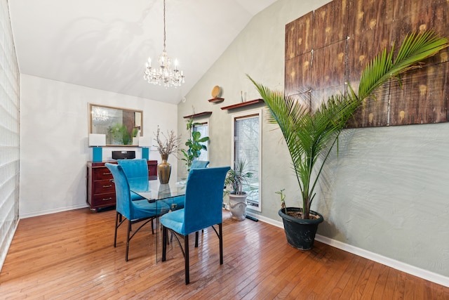 dining space with high vaulted ceiling, a notable chandelier, and light wood-type flooring