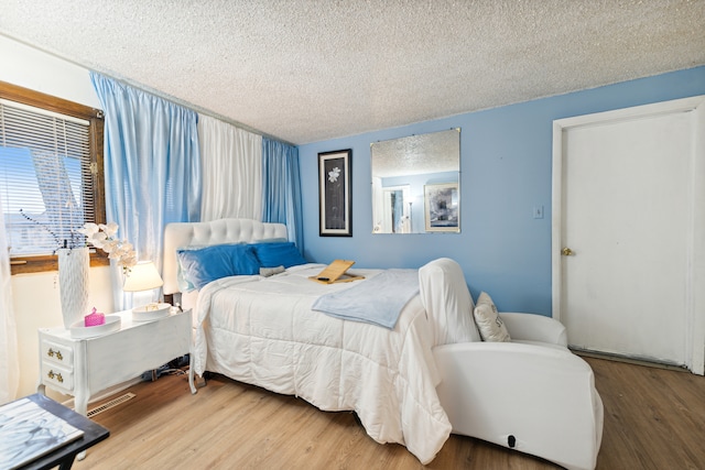 bedroom with hardwood / wood-style floors and a textured ceiling