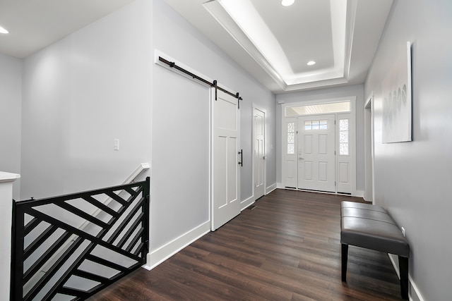 foyer entrance featuring dark hardwood / wood-style floors, a tray ceiling, and a barn door