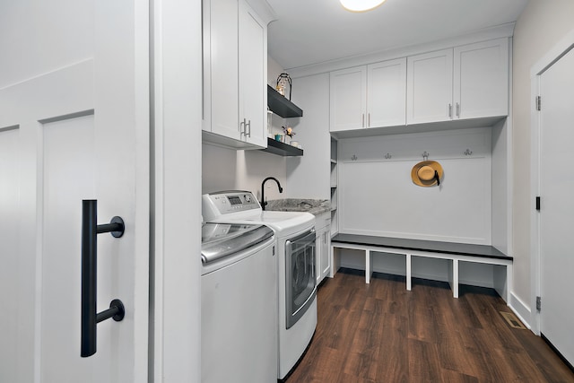 clothes washing area with sink, independent washer and dryer, dark hardwood / wood-style floors, and cabinets