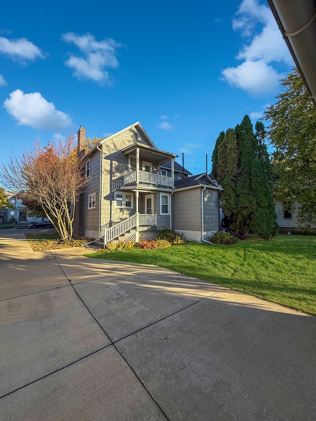 view of front of property featuring a front yard, a balcony, and a garage