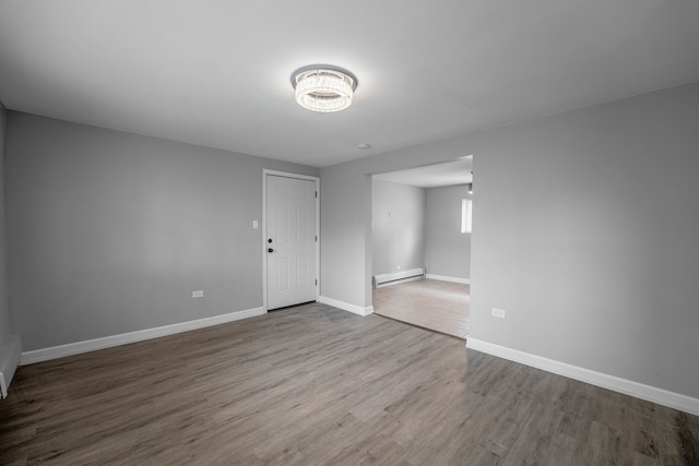 unfurnished room featuring wood-type flooring and a baseboard heating unit