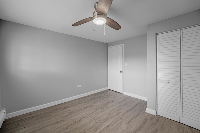 unfurnished bedroom featuring light hardwood / wood-style flooring, a baseboard heating unit, a closet, and ceiling fan