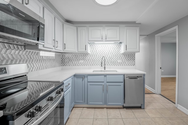 kitchen with sink, white cabinetry, stainless steel appliances, decorative backsplash, and light tile patterned floors