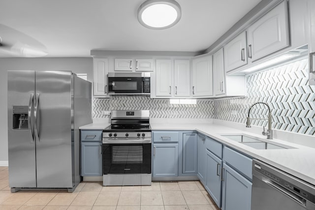 kitchen with appliances with stainless steel finishes, tasteful backsplash, sink, and light tile patterned floors