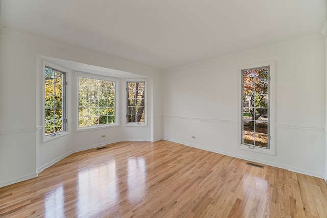 empty room with ornamental molding and light wood-type flooring