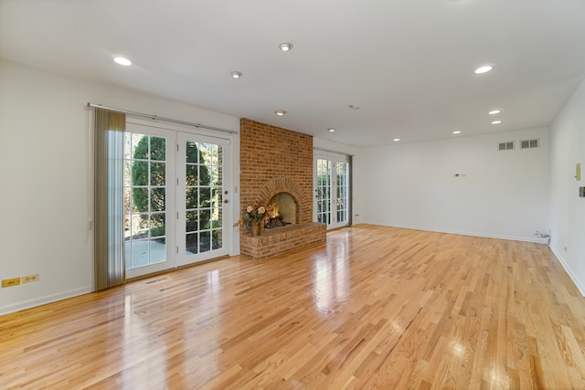 unfurnished living room featuring light hardwood / wood-style floors and a brick fireplace