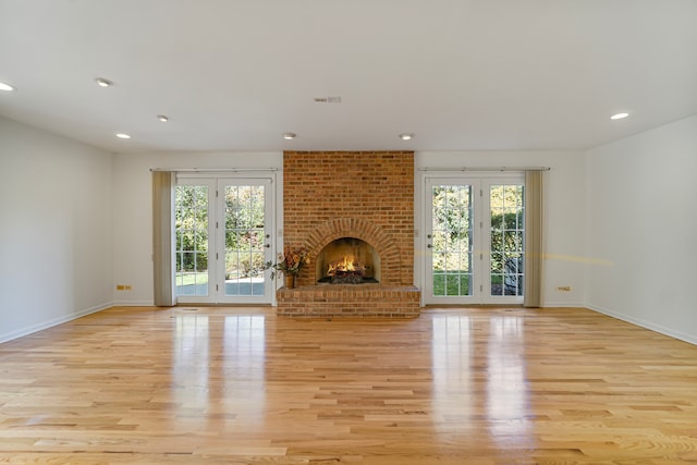 unfurnished living room featuring a fireplace, light wood-type flooring, and plenty of natural light