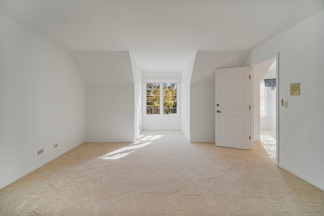 spare room with light carpet and vaulted ceiling