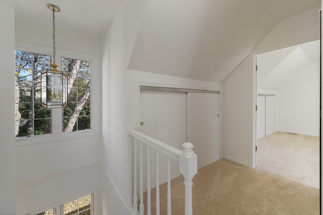 hallway with vaulted ceiling and light carpet