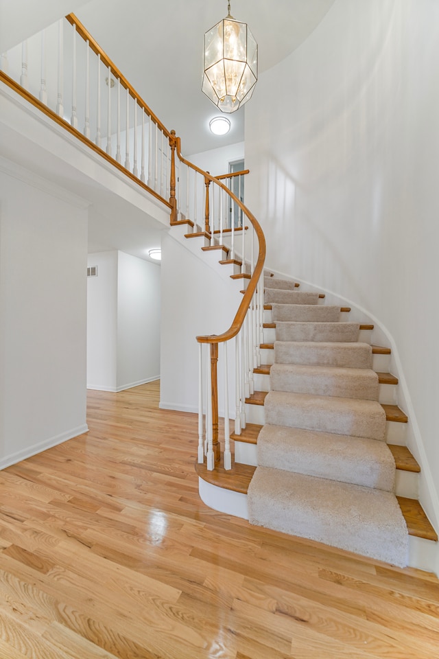 stairway featuring an inviting chandelier and hardwood / wood-style flooring