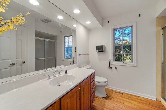 bathroom featuring vanity, toilet, a shower with shower door, and hardwood / wood-style floors