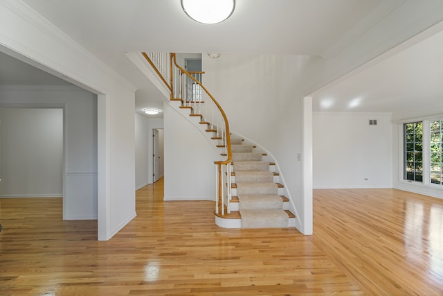 staircase with hardwood / wood-style flooring and ornamental molding