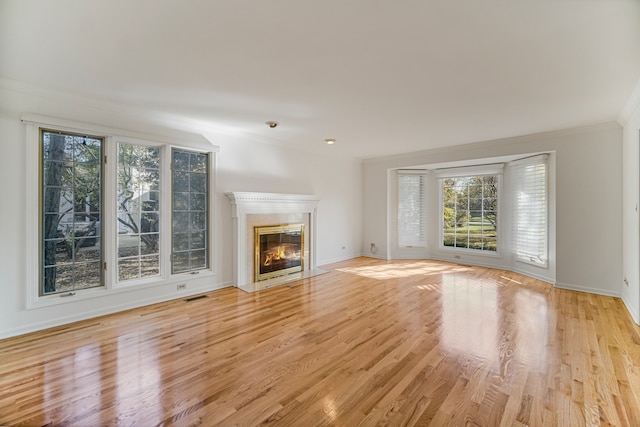 unfurnished living room featuring ornamental molding and light wood-type flooring