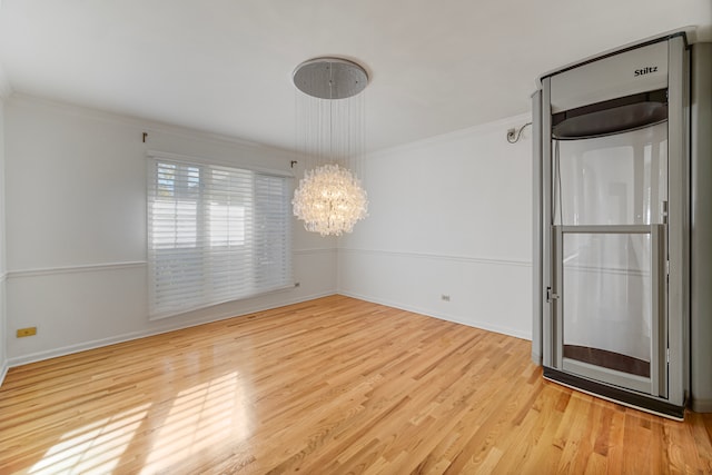 spare room with ornamental molding, a notable chandelier, and light hardwood / wood-style floors