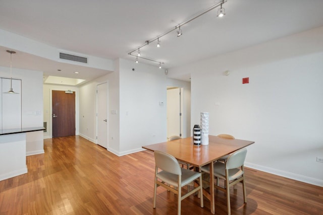 dining space featuring wood-type flooring and track lighting