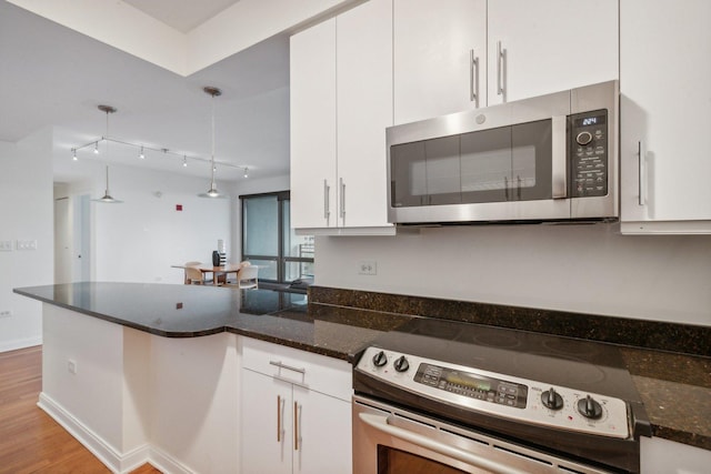 kitchen with white cabinetry, stainless steel appliances, dark stone counters, pendant lighting, and light wood-type flooring