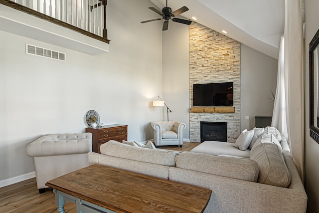 living room with hardwood / wood-style floors, high vaulted ceiling, a fireplace, and ceiling fan