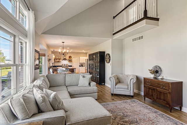 living room with a notable chandelier, hardwood / wood-style flooring, and a high ceiling