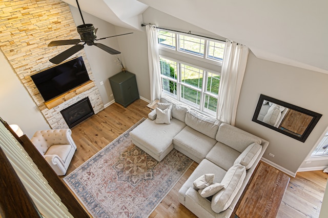 living room featuring ceiling fan, high vaulted ceiling, light wood-type flooring, and a fireplace