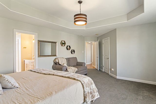 carpeted bedroom with ensuite bath and a tray ceiling