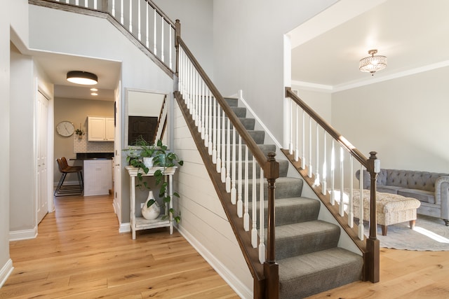 stairs with ornamental molding and hardwood / wood-style floors