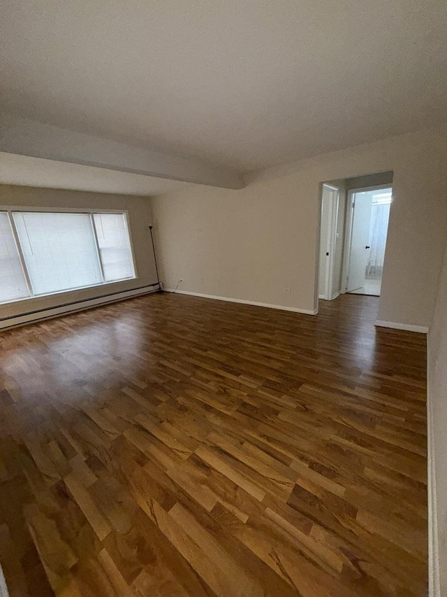 empty room with dark hardwood / wood-style flooring and a baseboard radiator