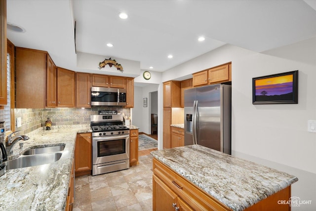 kitchen with a center island, backsplash, sink, light stone counters, and stainless steel appliances