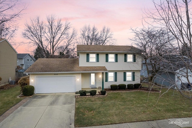 view of property featuring central air condition unit, a garage, and a lawn