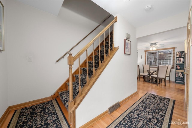 stairway featuring ceiling fan and wood-type flooring