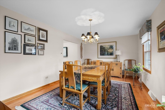 dining area with light wood-type flooring and an inviting chandelier