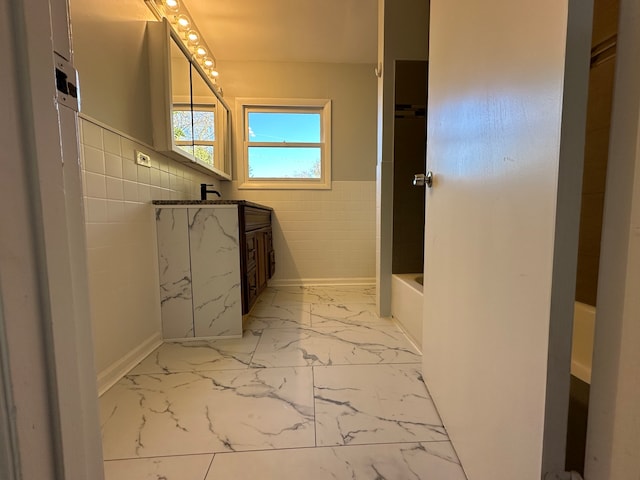 bathroom with vanity, a tub, and tile walls