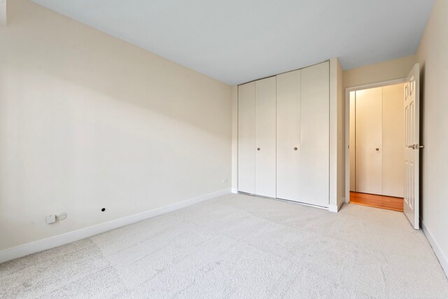 unfurnished bedroom with light carpet and a closet